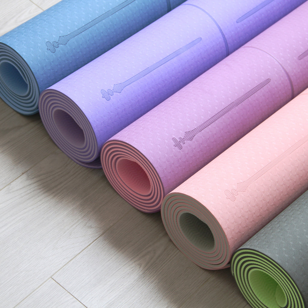 Colorful TPE yoga mats in blue, purple, pink, and green, rolled and ready for yoga practice. Available at Sportive Lives in Canada.