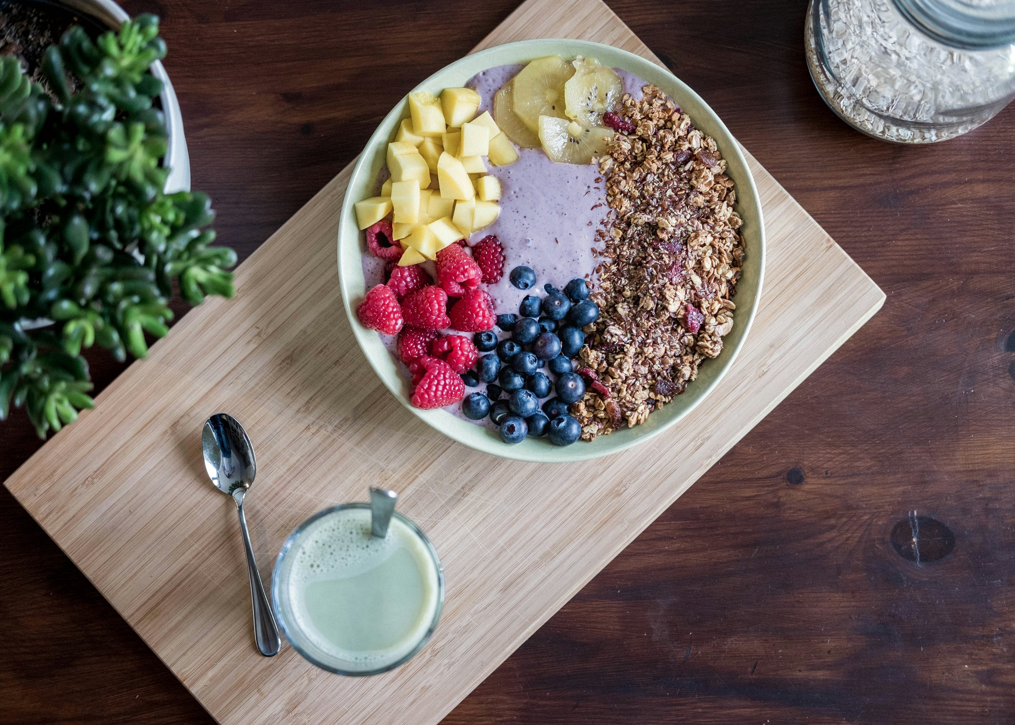 Healthy breakfast bowl with mixed berries, granola, and a green smoothie