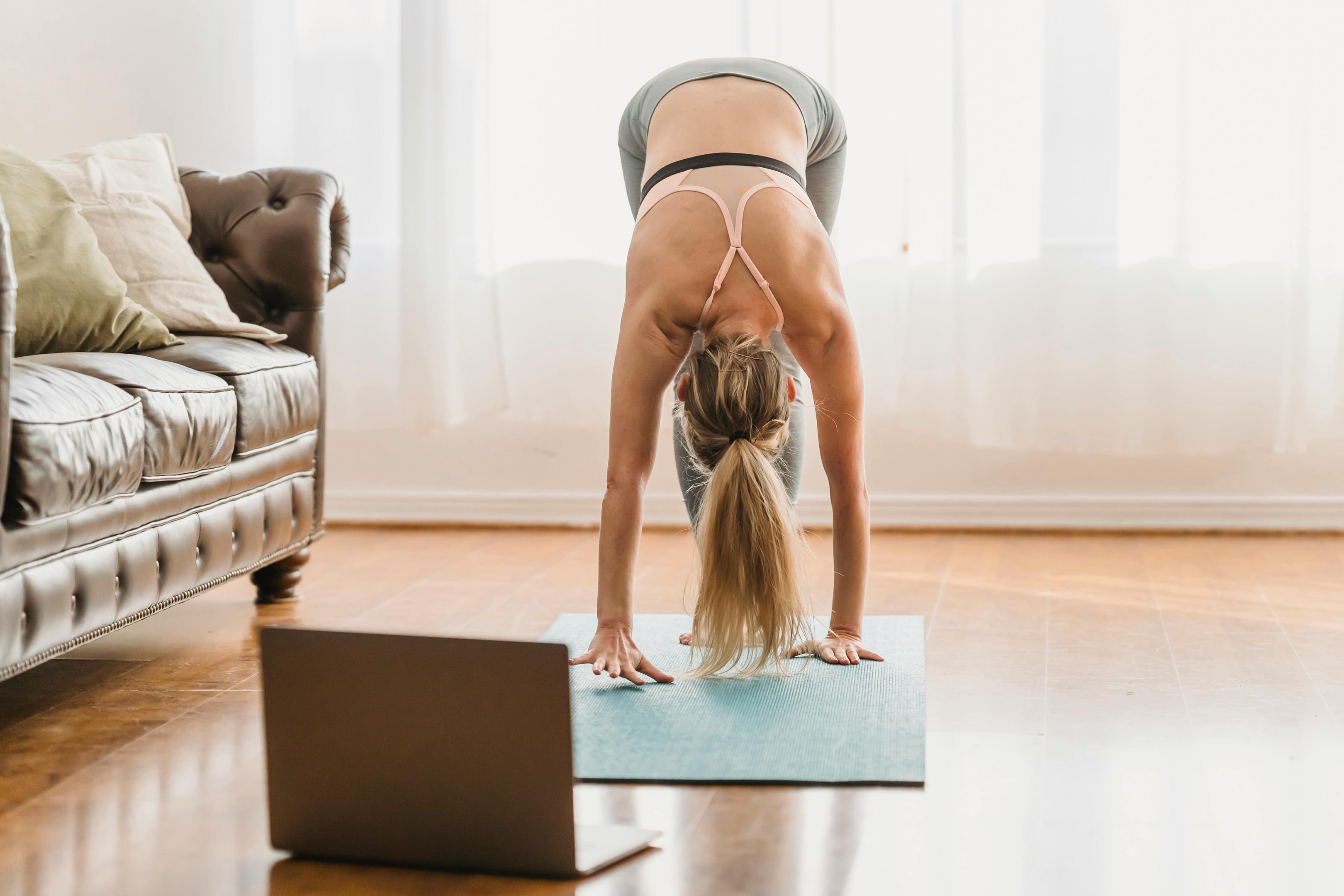 women practicing Standing Forward Bend (Uttanasana) indoors on yoga mats, showcasing proper form and posture.