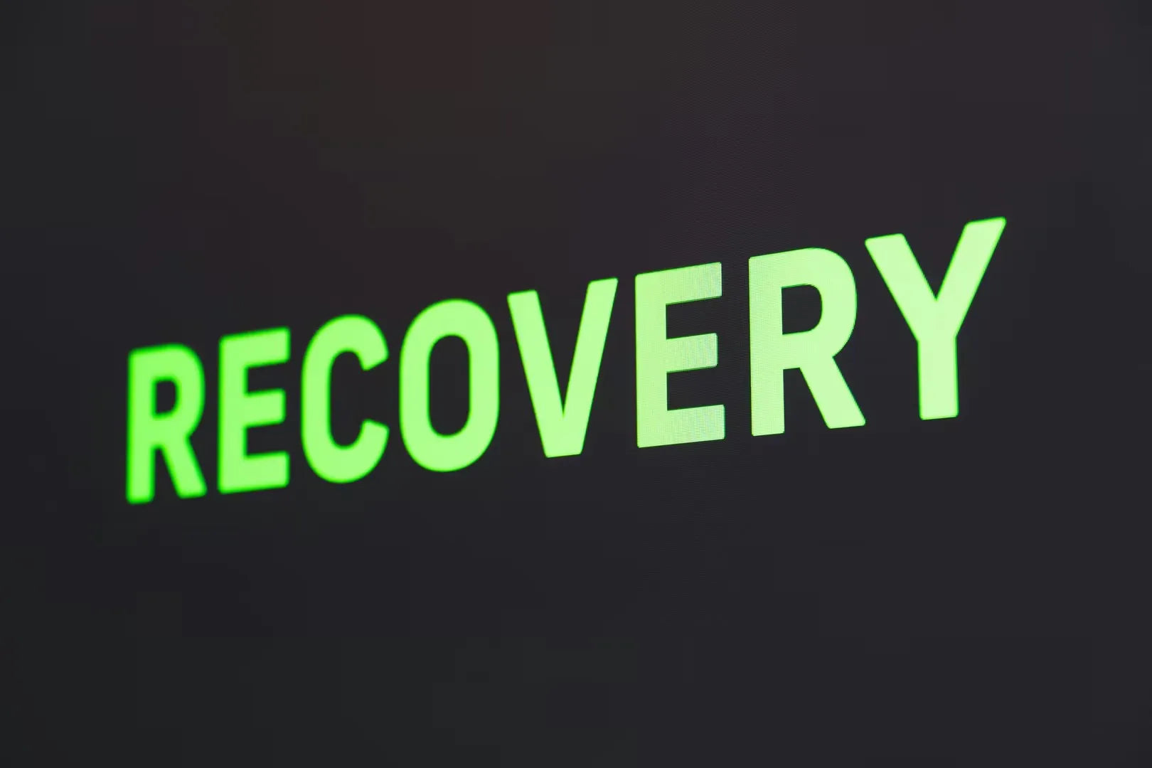 The word "Recovery" illuminated in green on a dark background