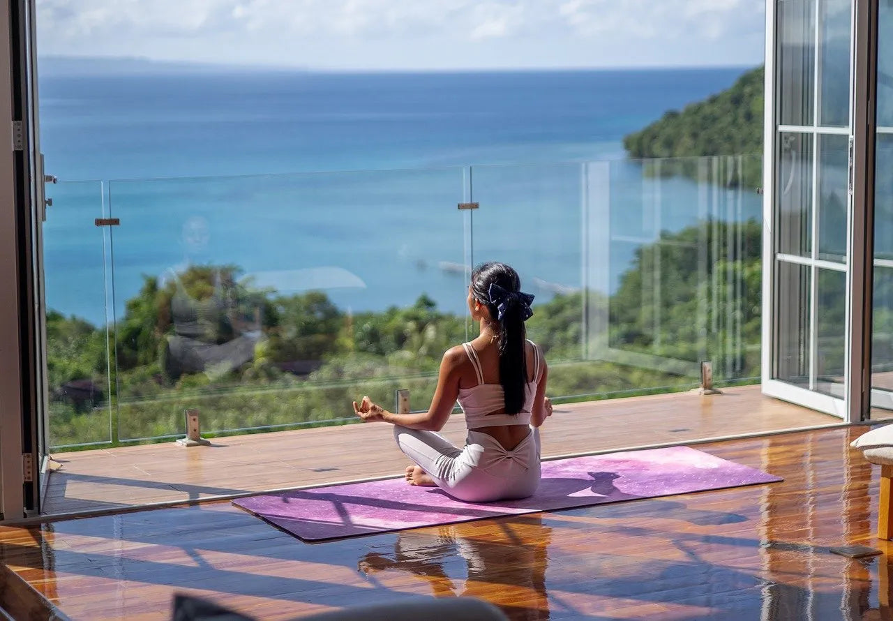 Women performing yoga meditation in front of a beautiful sea view