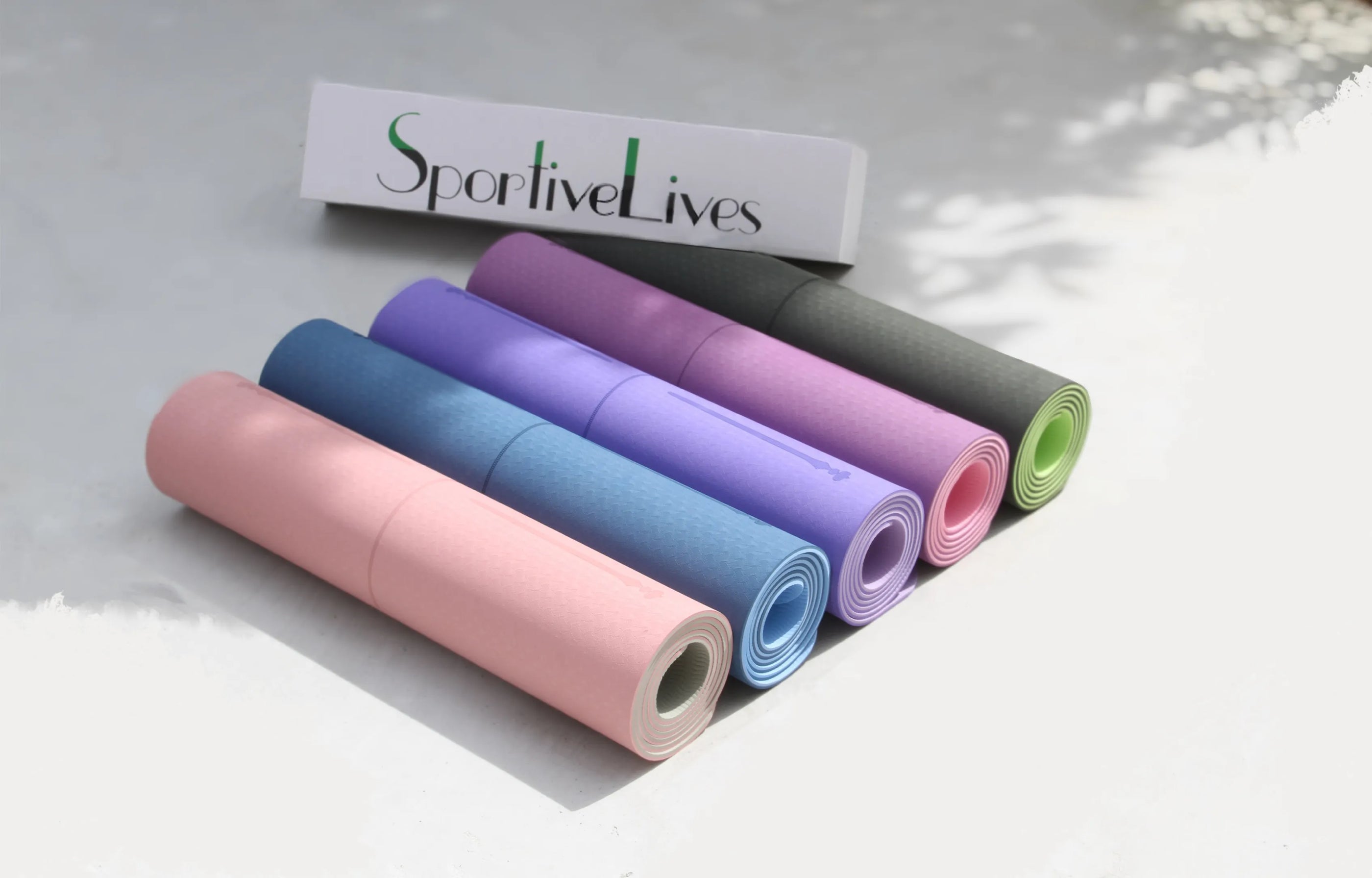 Five different colored yoga MATS are stacked together