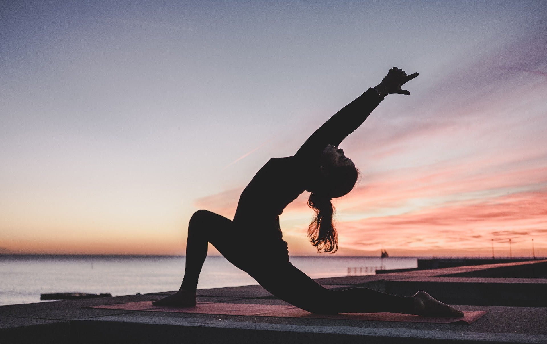 A woman doing yoga on the beach at dusk