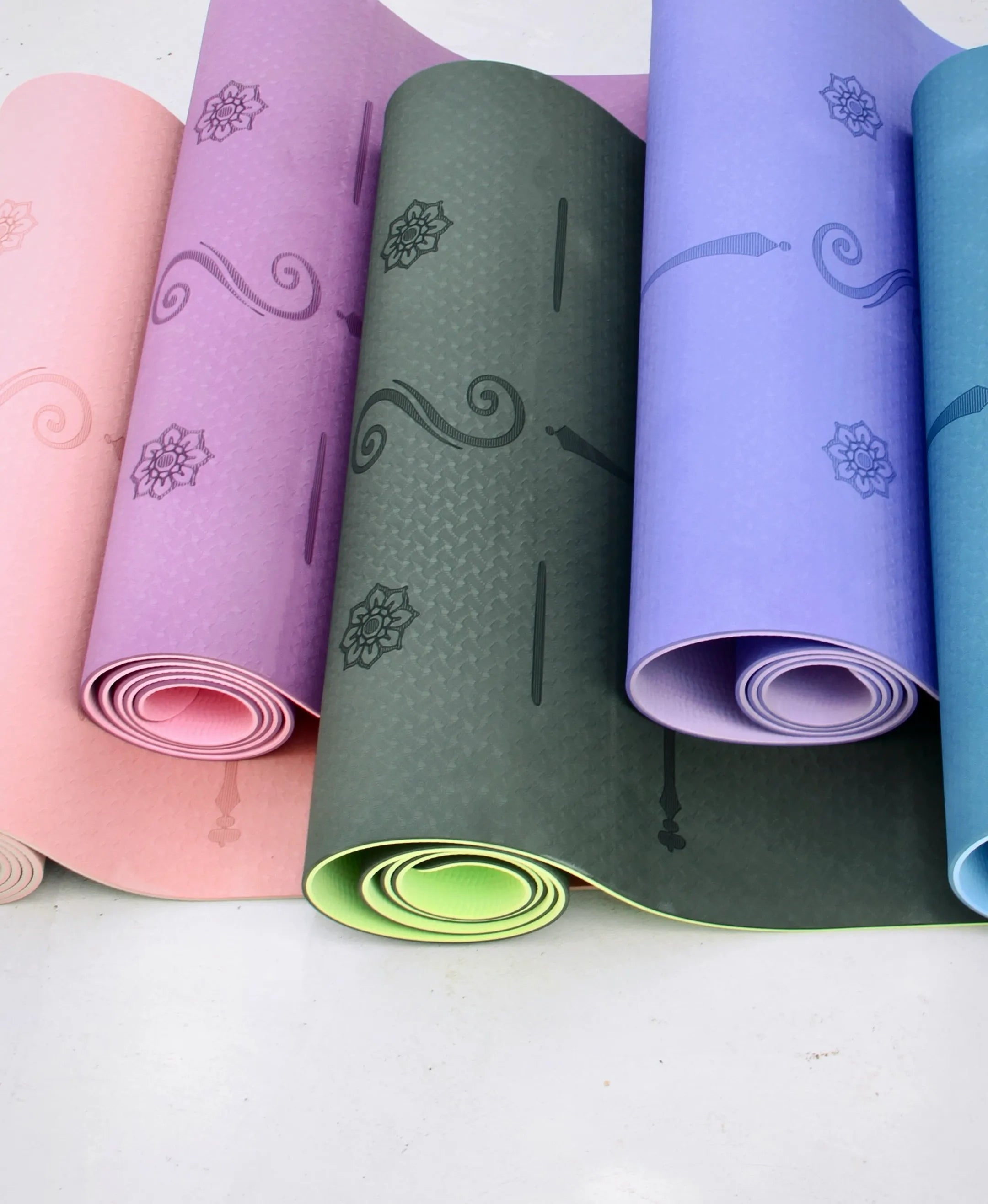 Yoga MATS of many colors are curled and stacked together