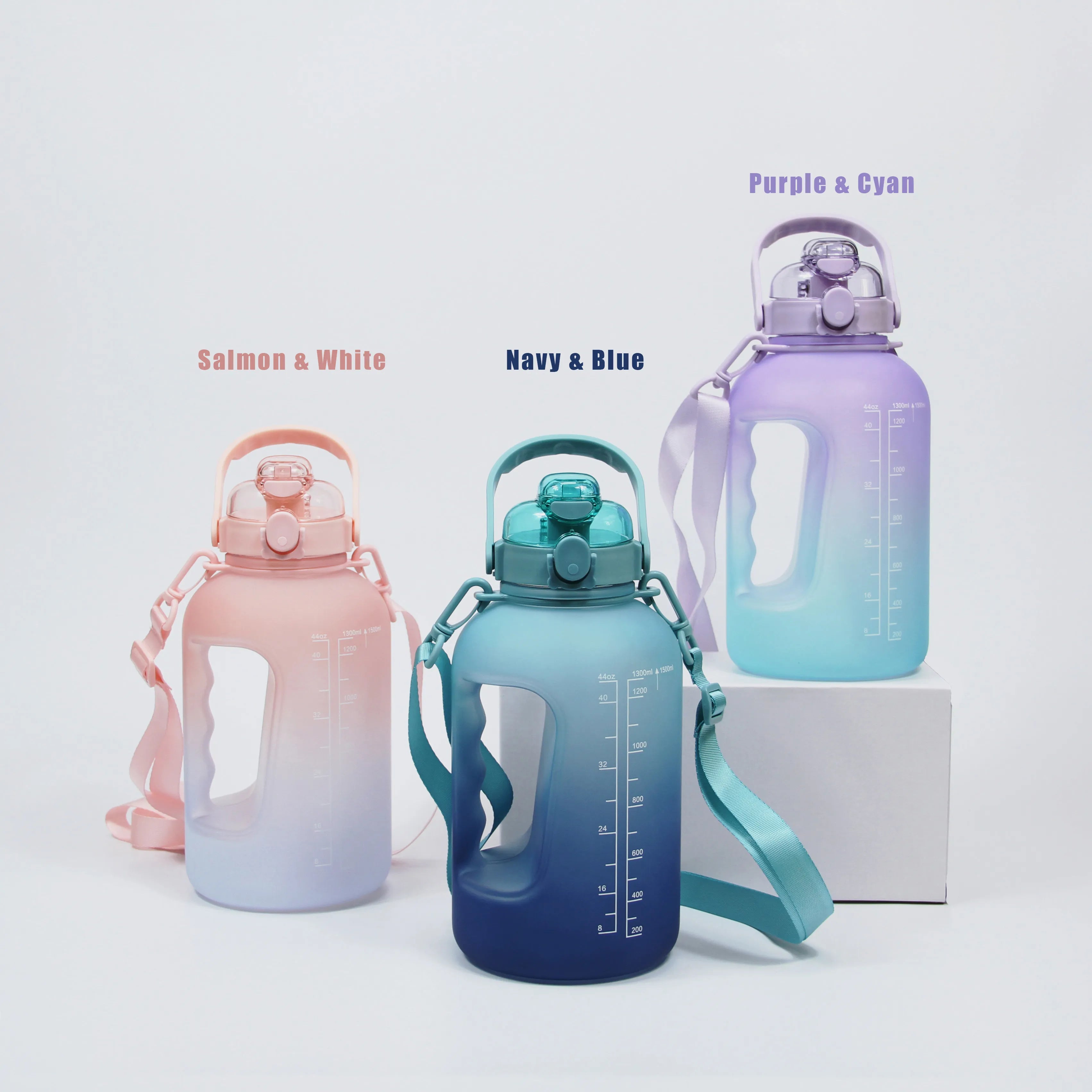 Three high-capacity water bottles with gradient color, in three color combinations: salmon and white on the left, navy and blue in the middle, purple and cyan on the right. Each water bottle comes with a removable shoulder strap and easy to carry handle.