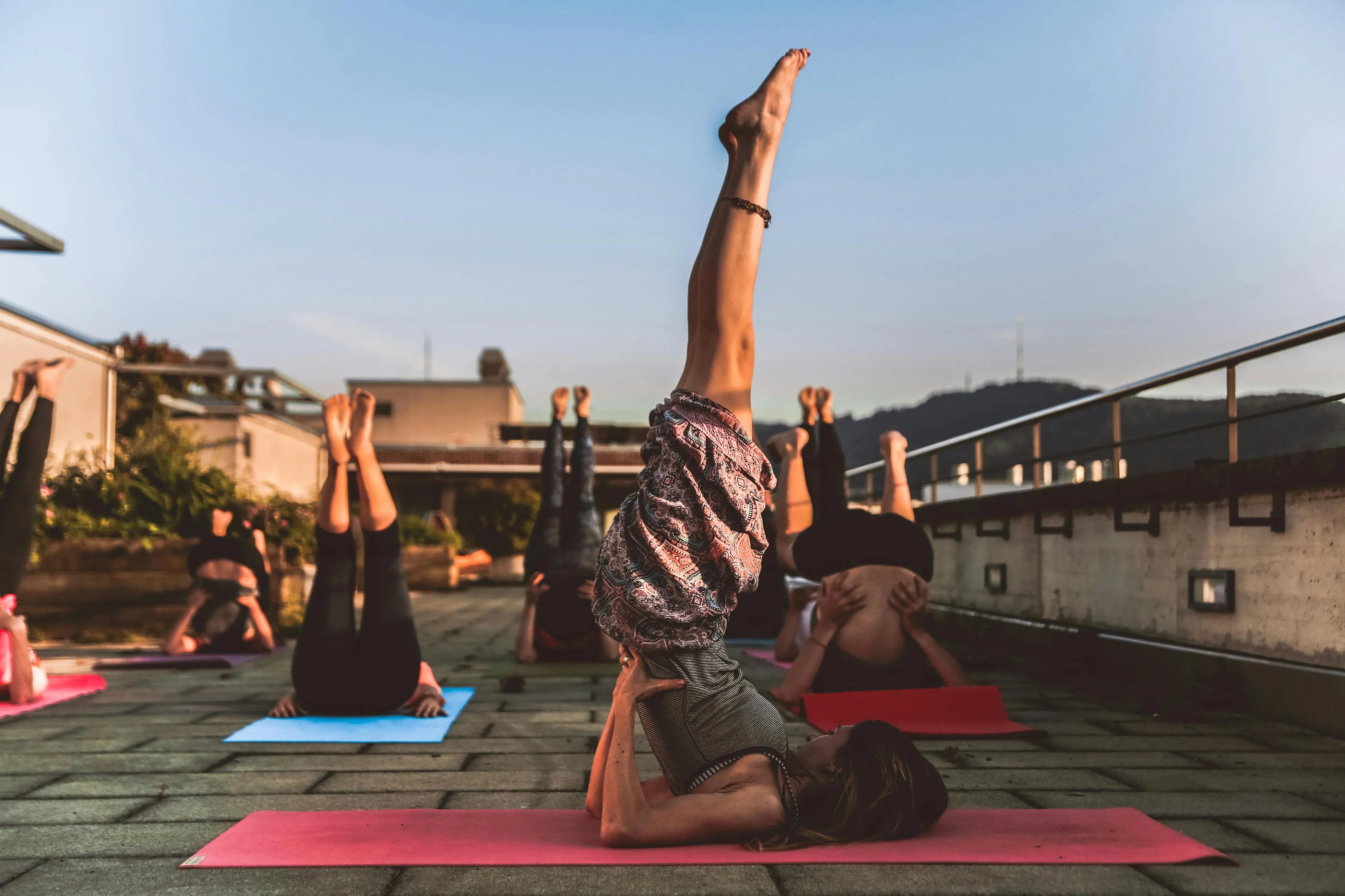 Group of yoga practitioners performing the Shoulder Stand pose during an outdoor yoga session, with a focus on alignment and balance, captured on Sportive Lives yoga mats in Canada.