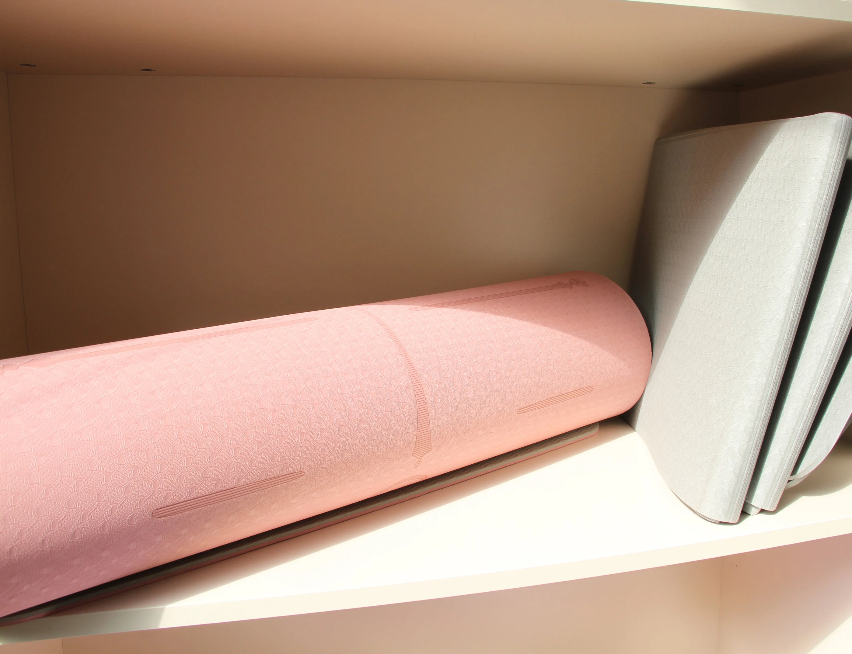 Sportive Lives pink and gray yoga mats stored on a shelf, ideal for home gym or studio use in Canada.