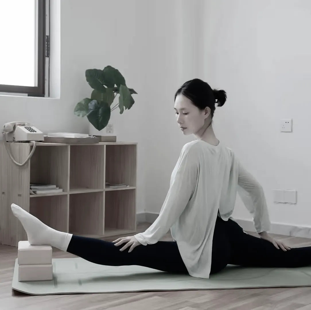 Woman performing a leg stretch with support from yoga blocks under her front foot to deepen the stretch.