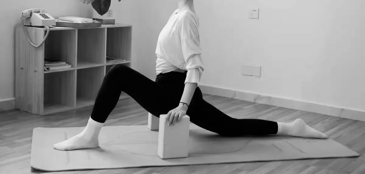 Woman practicing low lunge with yoga blocks for support under her hands, improving balance.